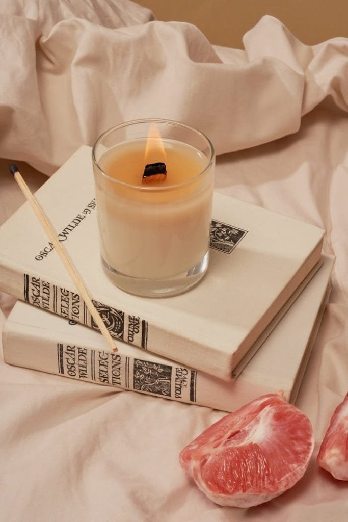 Aromatic candle and grapefruit on books create a warm, relaxing atmosphere.