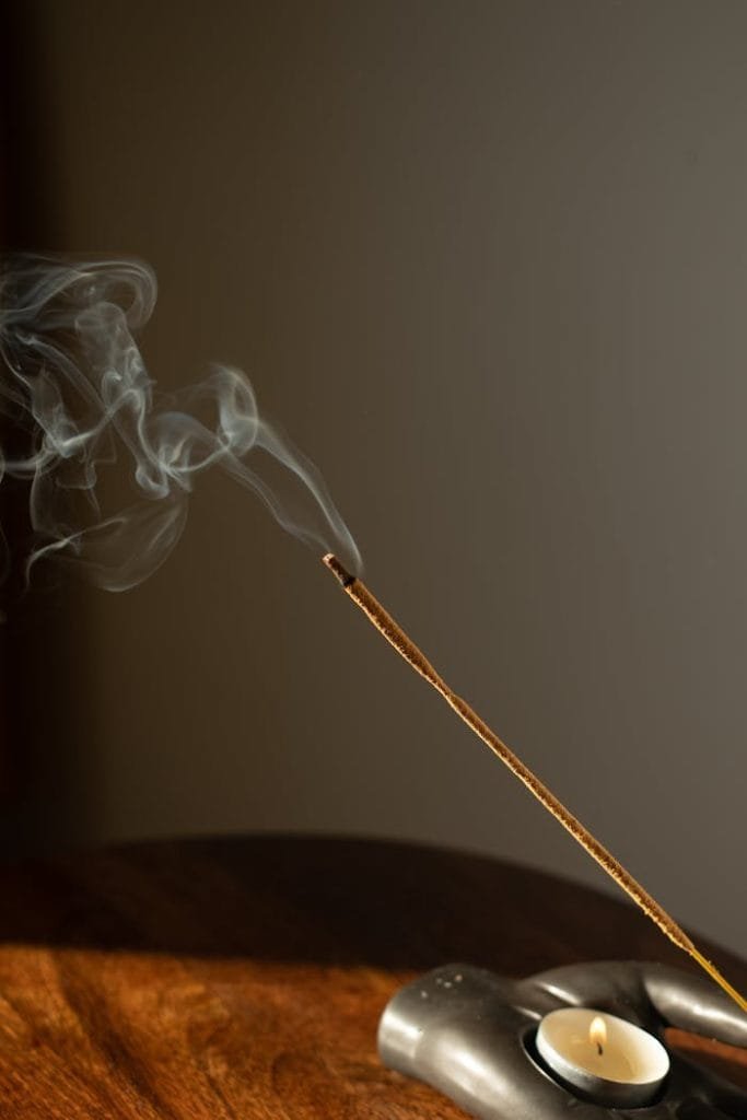 Close-up of an incense stick and tealight candle creating a calming ambiance.